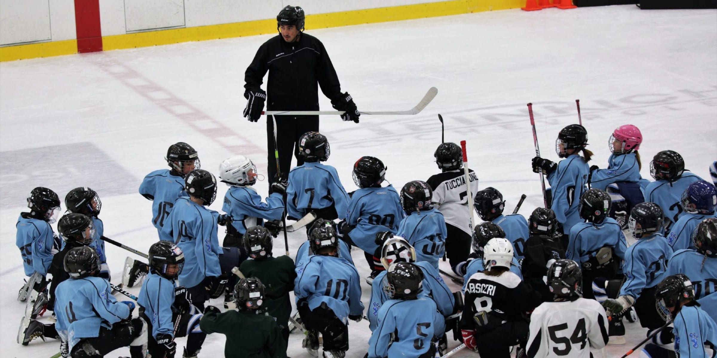 a person coaching some young hockey players